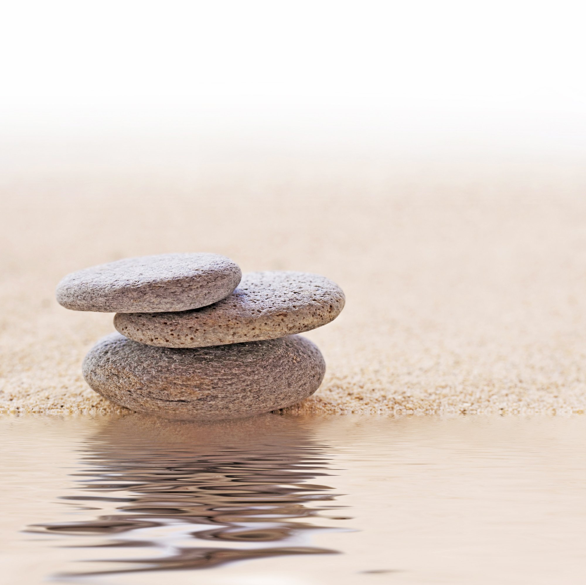 Zen stone stack and sand, water reflections